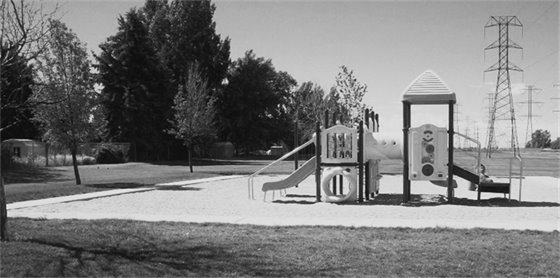 Photograph of Powerline Park featuring playground, greenery, and views of the powerlines.